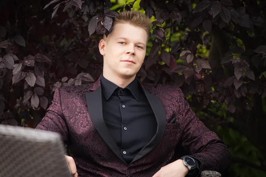 Mężczyzna w bordowej marynarce we wzór i czarnej koszuli